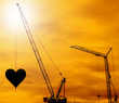 Heart hang in construction cranes silhouettes sunset