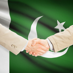 Businessmen handshake with flag on background - Pakistan