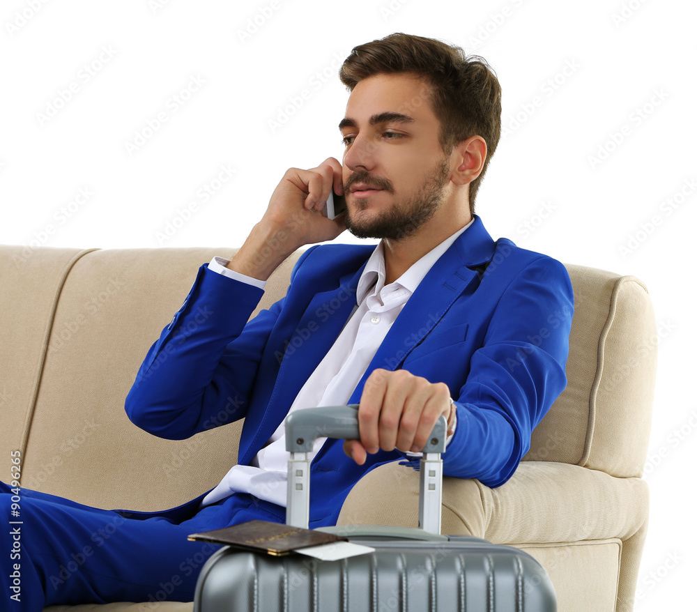 Business man with suitcase sitting on sofa isolated on white