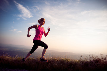 beautiful young woman runns cross country on a mountian path at