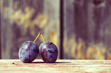 Two Plums On A Wooden Surface Close Up. A Beautiful Background With Plums In Vintage Tones
