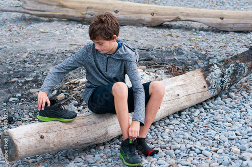 Child Sitting On A Rocky Beach Putting His Shoes This Stock Child Sitting On A Rocky Beach Putting His Shoes