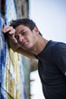 Attractive young man leaning against graffiti wall