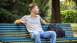 Handsome blond young man sitting on park bench