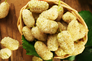 Poster - Fresh mulberry in wicker basket on wooden table, closeup