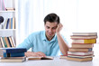 © Africa Studio - Young man reading book at table in room