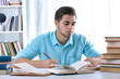 © Africa Studio - Young man reading book at table in room