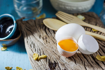 Still life broken white eggs and egg yolk on a wooden rustic bac