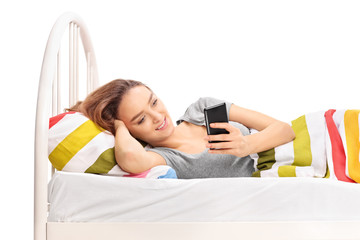 Wall Mural - Woman lying in bed and looking at her phone