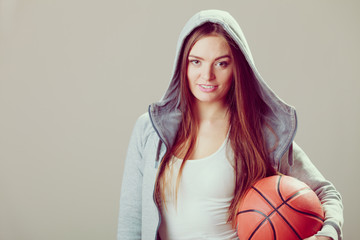 Sporty teen girl in hood holding basketball.