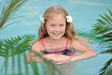 portrait of little girl in tropical style in a swimming pool