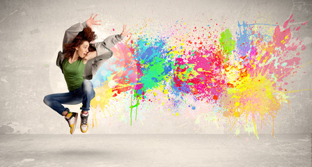 Wall Mural - Happy teenager jumping with colorful ink splatter on urban backg