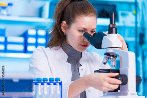 Fotografia, Obraz Female scientist looking through a microscope in laboratory