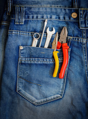 Several tools on a denim workers pocket.