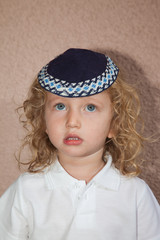 The charming little boy with blond curls in Jewish kippah