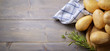 Potatoes and rosemary on wooden background, top view, space for text.