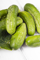 Wall Mural - fresh organic cucumbers on a white wooden background.