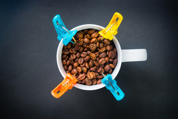 Coffee beans in a cup Decorated with clothespin on black backgro