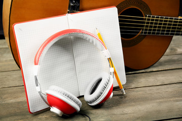 Wall Mural - Music recording scene with classical guitar, memo pad and headphones on wooden table, closeup