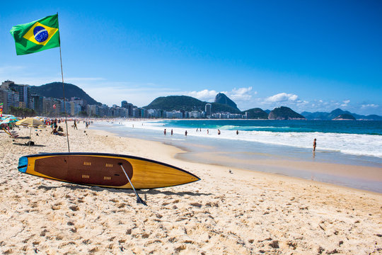 brazilian flag and surfboard at copacabana beach, rio de janeir