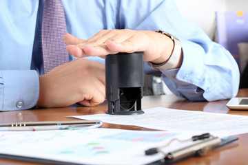 Wall Mural - Close-up Of Businessman Hand Pressing a  Stamp On Document in th