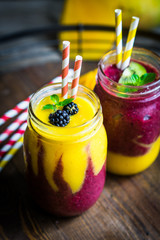 Canvas Print - Colorful two layer smoothies with mango and berries on rustic wo