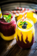 Canvas Print - Colorful two layer smoothies with mango and berries on rustic wo