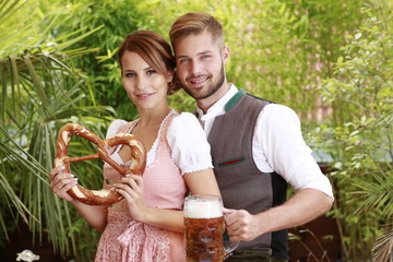 Wall Mural - Attraktives bayrisches Paar in Tracht mit Bier und Brezel