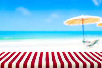 Wall Mural - Table covered with striped tablecloth on blurred beach background