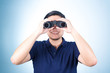 © pookpiik - Asian guy holding binoculars, on blue background