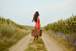 © gorosi - Picture of beautiful young lady on rural road holding suitcase