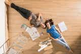 Fototapeta  - Top view, a modern couple lying on the floor of their new home
