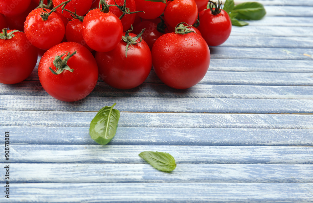 Fresh cherry tomatoes with basil on wooden table close up