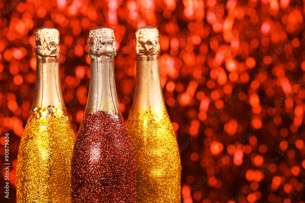 Decorated champagne bottles on bright sparkling blurred background