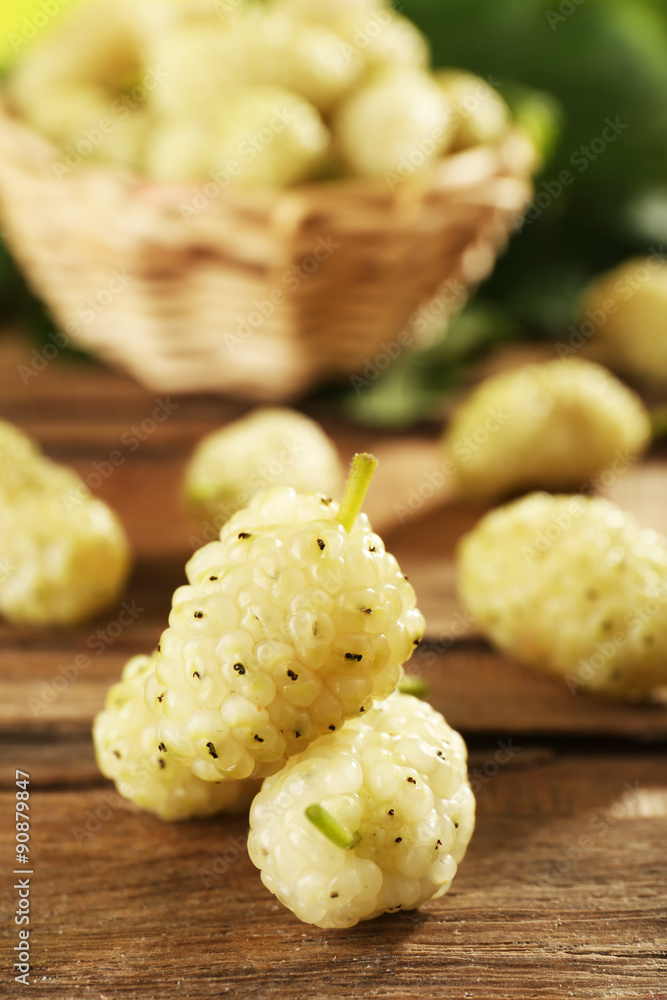 Fresh mulberry in wicker basket on wooden table, closeup