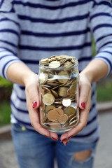 Poster - Woman holding money jar with coins outdoors