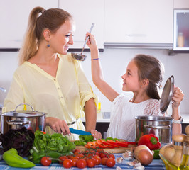 Wall Mural - Mother with daughter cooking veggies