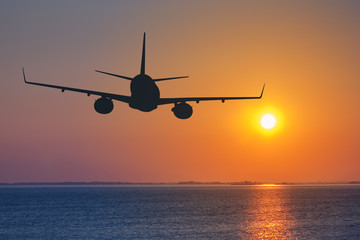 Wall Mural - silhouette of passenger airplane flying on sunset