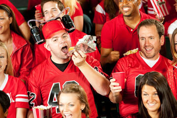 Wall Mural - Fans: Male Fan Eats Hot Dog With Beer Helmet On