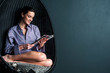 Relaxed woman on bubble chair reading magazine
