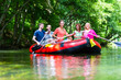 Friends paddling on rubber boat at forest river or creek