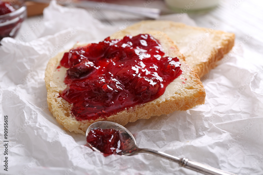 Bread with butter and homemade jam on crumpled parchment, closeup