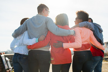 Wall Mural - group of happy teenage friends hugging on street
