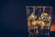 Glass Of Whiskey On Black Background With Reflection, Warm Atmosphere