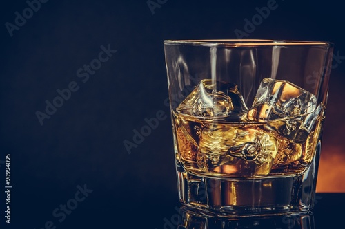 Fotografía glass of whiskey on black background with reflection, warm atmosphere