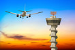 Commercial airplane take off over airport control tower at sunse