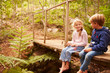 © Monkey Business - Young siblings sitting on wooden bridge in a forest