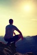 © rdonar - Young man in black sports pants and grey shirt  is sitting on cliff's edge and looking to misty valley bellow