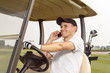 © LENSLOGIC - Man sitting in a golf cart and talking on phone