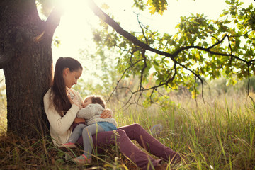 young mother feeding toddler outdoors